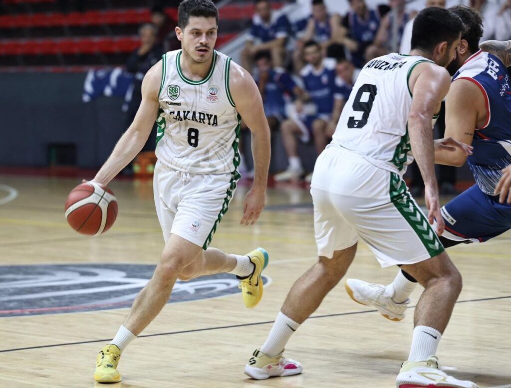 Kütahya BSK oyuncusu topu kontrol ederken, maç heyecanı tribünlerde devam ediyor.